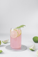 Grapefruit juice in a glass with slices of green lemon garnish, pink grape juice in a can shaped glass with lemon slices