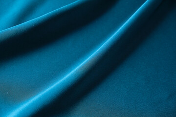 Blue silk drapery and upholstery fabric from the courtyard. Blue satin, silky fabric, wave, draperies. Beautiful textile backdrop. Close-up. Top view