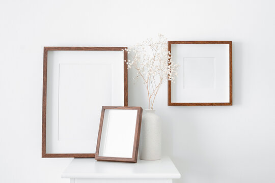 Vertical and square wooden frames mockup for artwork, photo, print and painting presentation. White walll with vase and dry gypsophila decorations.
