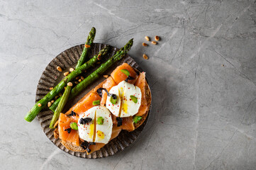 Sandwiches with smoked salmon and asparagus on the light stone background, top view. Space for text. Healthy lunch.