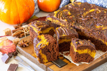 Thanksgiving Day homemade baking. Chocolate brownie pumpkin puree cake dessert with spices on a stone table.