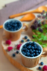 In ceramic cups there is a fresh and ripe wild berry blueberry
