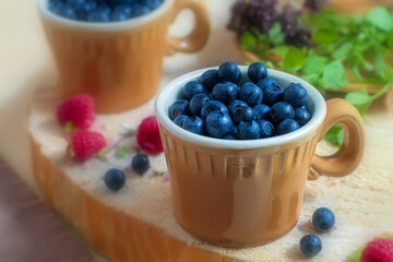 On a wooden round stand there is a small cup with blueberries