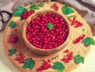 A red currant is lying in a wooden plate on a wooden tree cut in a wooden plate