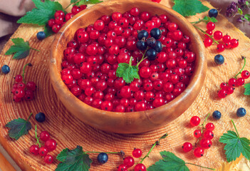 Ripe and juicy red currants are lying in a wooden bowl