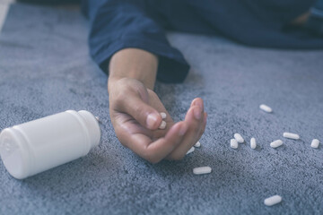 Woman's hand holding a scattered pill bottle kills herself by overdosing. Depression and drug overdose or the idea of a problem (Post-traumatic stress disorder)