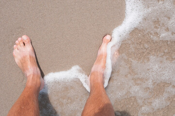 Tanned bare men's feet on  a sea coast