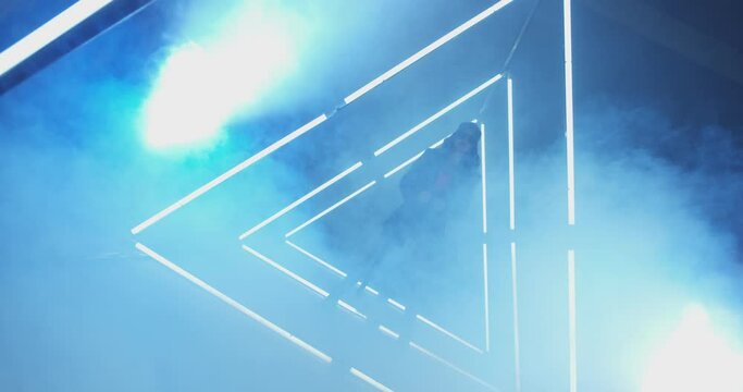 4K Professional swag freestyle dancer . Stylish young girl dancing with real strobe lights . Against blue background with triangle shape of led lights . Showing heart by fingers during dance . 