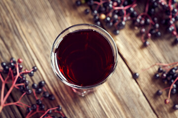 A shot of black elder syrup with fresh elderberries. Alternative remedy against viruses.
