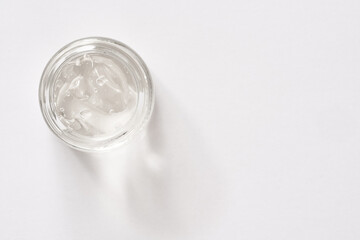 Aloe vera gel in a glass glass jar on white background, top view. Healthy cosmetic product.