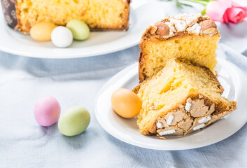 Piece of traditional italian Easter cake Colomba and Easter marzipan eggs in pastel colors, close up