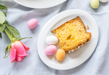 Piece of traditional italian Easter cake Colomba and Easter marzipan eggs in pastel colors, top view