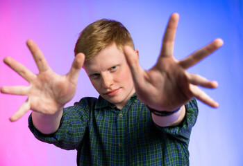portrait of a red-haired guy in a green shirt and jeans on a colored background. the teenager...