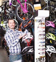Man is choosing the safest helmet for cycling in sports store.