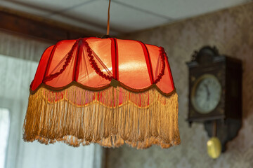 Vintage lampshade made of red fabric with fringes as an element of the decor of the interior of the room