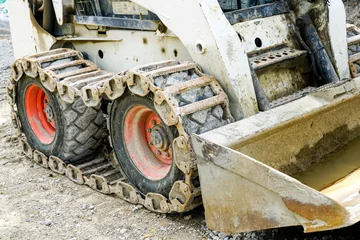 Poster skid loader or bobcat with metal tracks on rubber tires © Zigmunds