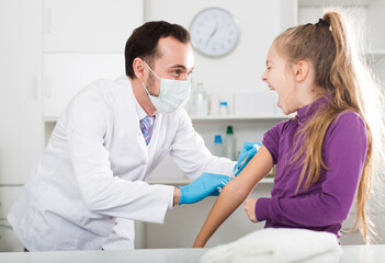 Fototapeta premium Male doctor using syringe to make injection to young female patient in hospital