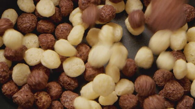 Brown choco cereal balls falling into a bowl, close up