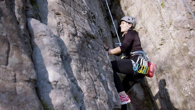 Senior woman climbing rocks outdoors in nature, active lifestyle.