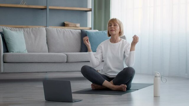 Older Lady Meditating At Laptop With Eyes Closed At Home