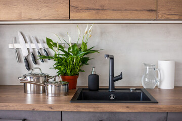 Modern kitchen in grey colors and wooden cupboards at home with kitchenware