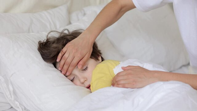 Worried parent call doctor nervous of child fever. Mom touch hot forehead of sleeping boy make phone call to pediatrician. Caring mum treating sick kid at home. Family healthcare and health concept