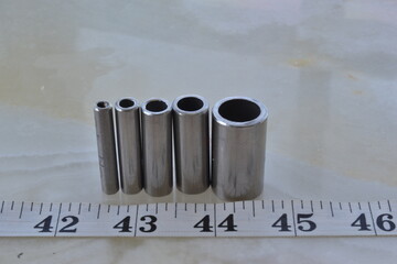 four tubes made of stainless steel in different diameters with measuring tape