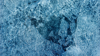 Beautiful ice texture with cracks of a frozen puddle on the asphalt for 3d texturing or design.