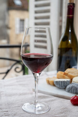 Tasting of burgundy red wine from grand cru pinot noir  vineyards with french goat cheeses and view on old town street in Burgundy wine region, France