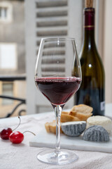 Tasting of burgundy red wine from grand cru pinot noir  vineyards with french goat cheeses and view on old town street in Burgundy wine region, France