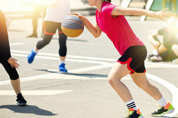 Girls teenagers play street basketball
