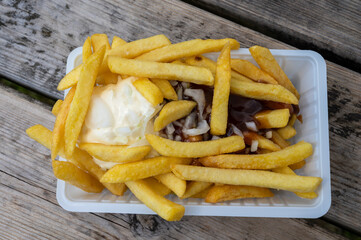 Portion of french fried potato chips with curry and mayonnaise sauce and onion
