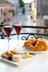 Drinking of Kir Royal,  French aperitif cocktail made  from creme de cassis topped with champagne, typically served in flute glass, with view on old French village