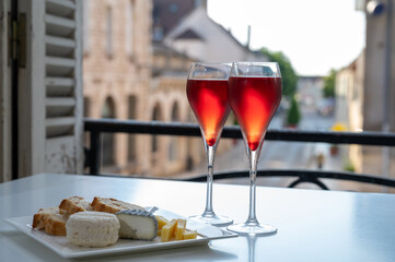 Drinking of Kir Royal,  French aperitif cocktail made  from creme de cassis topped with champagne, typically served in flute glass, with view on old French village