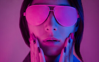 Portrait of a young woman in neon light with a surprised expression on her face.