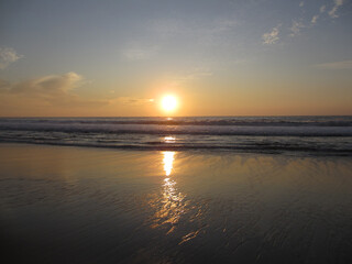 Fototapeta na wymiar Sunset over ocean waves as they reach the beach