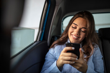 Woman with smartphone on the back seat of a car. Young girl uses a mobile phone in the car. Technology cell phone isolation. Internet and social media. Woman with smartphone in her car