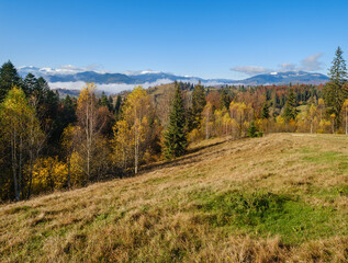 Fototapeta na wymiar Late autumn mountain morning scene with snow covered tops in far and foggy clouds in valleys. Picturesque traveling, seasonal, nature and countryside beauty concept scene. Carpathians, Ukraine.