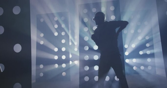 4K Professional Hip Hop , freestyle or swag dancer . Stylish young man dancing near decorative walls with many circle holes and spotlight . Real decoration . Shot on RED HELIUM Camera in Slow Motion .