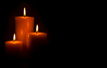 Three Pillar Candles Burning in a Dark Room
