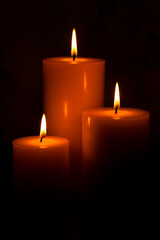 Three Pillar Candles Burning in a Dark Room