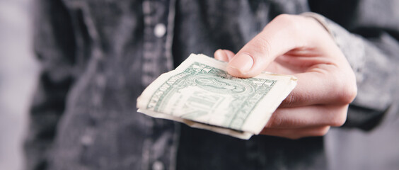 young woman gives money on gray background