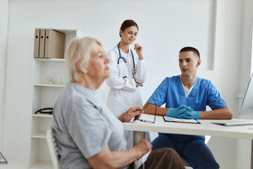 male doctor with a nurse examining an elderly woman health hospital