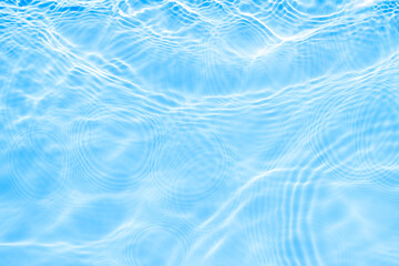 Surface of light on blue transparent swimming pool water. Trendy abstract wavy background. Water waves in sunlight with copy space