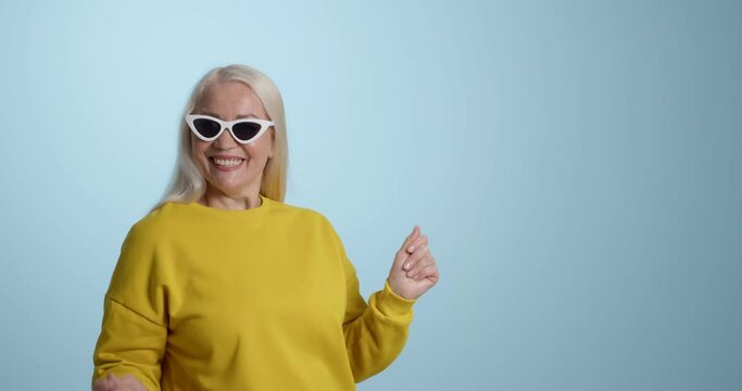Happy mature woman dancing against color background
