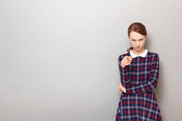 Portrait of serious young woman pointing with index finger at you