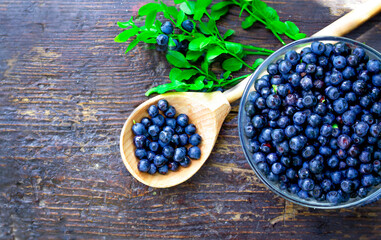 Forest blueberries on a wooden table in a plate and spoon. The concept of correct and healthy food.