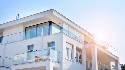 Modern white facade of a residential building with large windows. View of modern designed concrete apartment building.