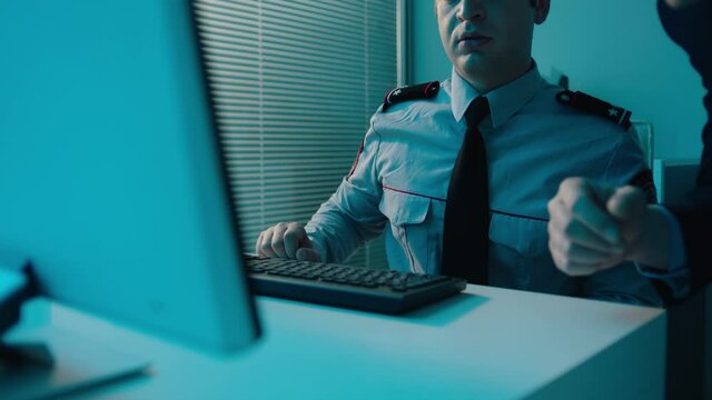 Police detectives working together in computer room to try and solve a case . Men at desk in room with data on screens .  Staged shot with fictional uniforms, so property release not required .