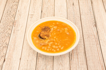 First plate of typical Spanish food of popular fabada with white beans stewed with verdura, meats and sausages of the country on wooden table